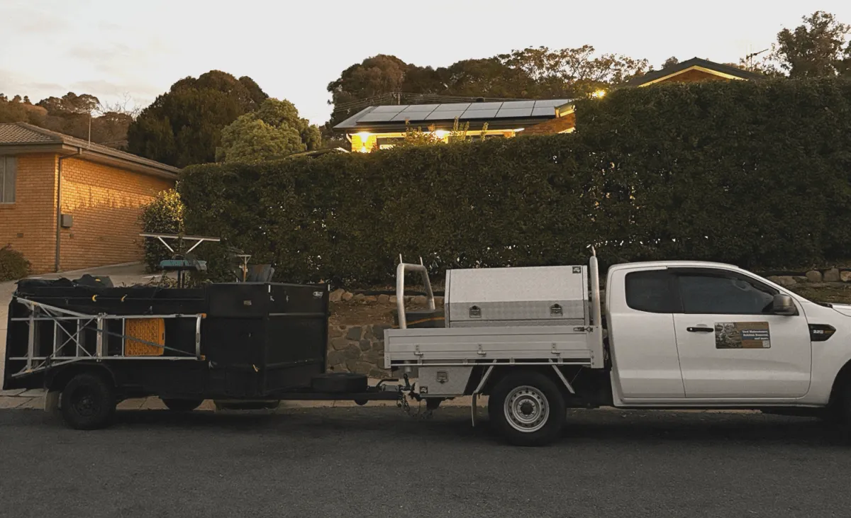 A professional using a lawn mower to provide DVA lawn care services in a sunny Canberra garden.